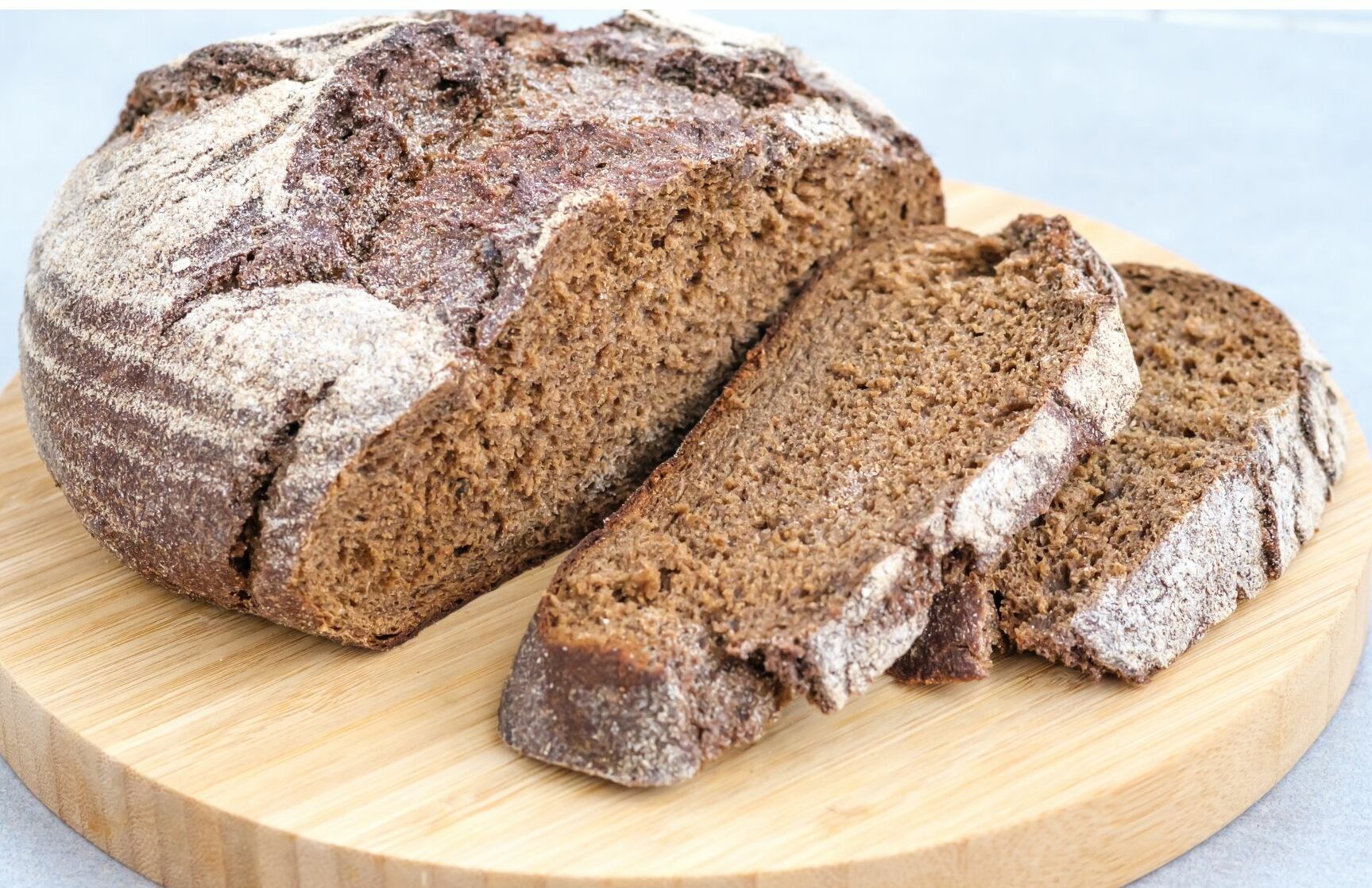Tranches de pain de seigle à la mie dense posées sur une planche en bois